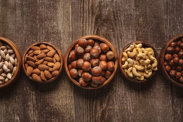 Top view of nuts in bowls arranged on wooden tabletop — Stock Photo