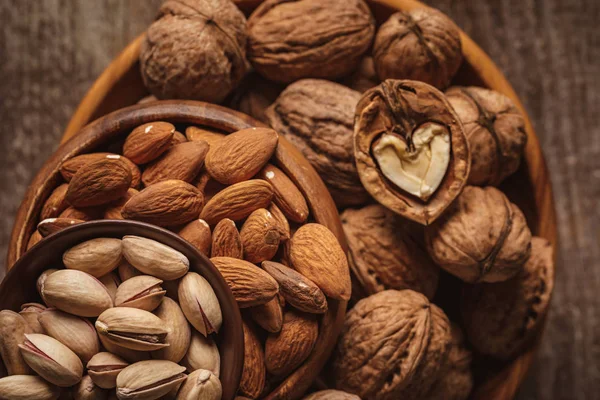 Top view of almonds, pistachio nuts and walnuts in bowls on wooden surface — Stock Photo