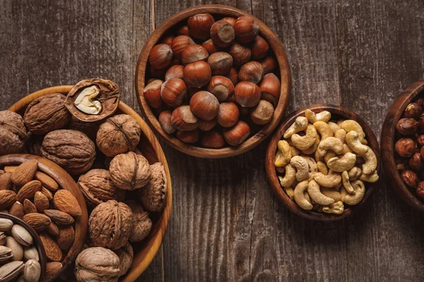 Top view of nuts in bowls arranged on wooden tabletop — Stock Photo