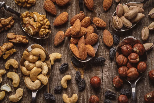 Flat lay with nuts in spoons on wooden tabletop — Stock Photo