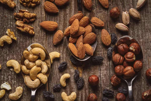 Flat lay with nuts in spoons on wooden tabletop — Stock Photo