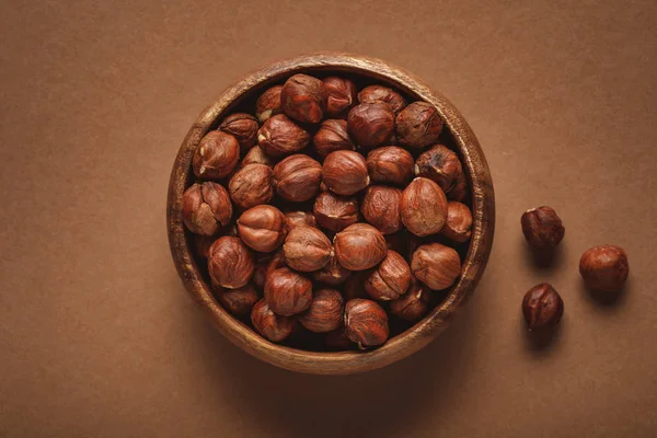 Top view of in wooden bowl on hazelnuts brown background — Stock Photo