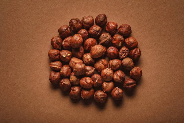 Top view of pile of shelled hazelnuts on brown backdrop — Stock Photo