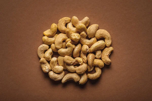 Top view of pile of cashew nuts on brown background — Stock Photo