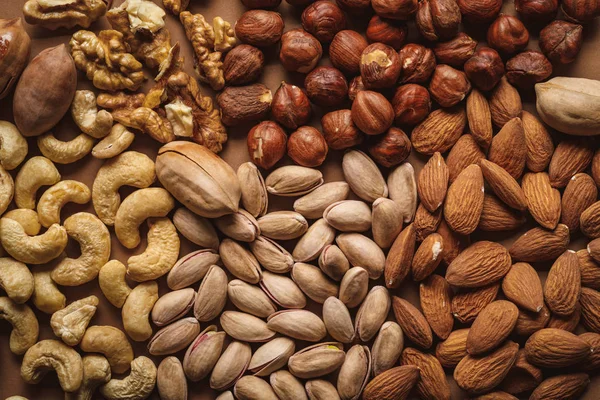 Disposición plana con sabrosos frutos secos sobre fondo marrón - foto de stock