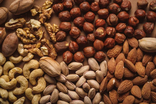 Disposición plana con sabrosos frutos secos sobre fondo marrón - foto de stock