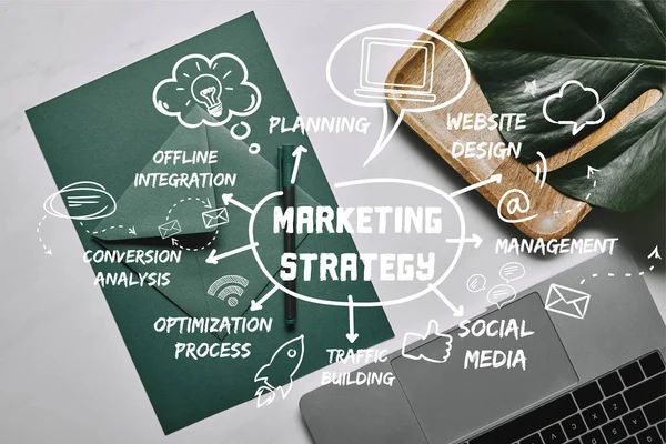 Livro verde para modelo de carta por laptop sobre fundo de mármore branco com ícones de estratégia de marketing — Fotografia de Stock