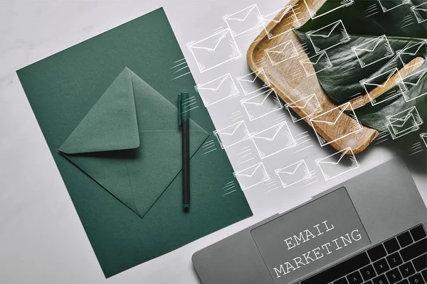 Grünes Papier für Briefvorlage per Laptop auf weißem Marmorhintergrund mit E-Mail-Marketing und Symbolen — Stockfoto