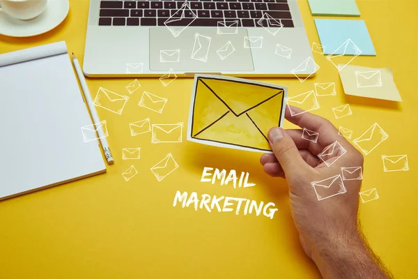 Cropped image of man holding envelope sign near laptop with 