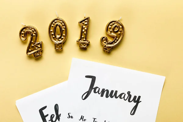 Golden 2019 candles and winter calendar on beige — Stock Photo