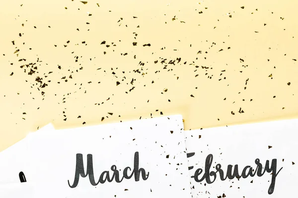 Top view of march and february calendar and golden confetti on beige background — Stock Photo