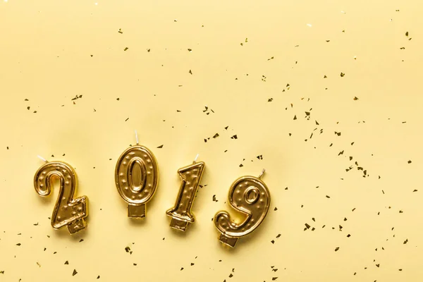 Вид зверху на золоті свічки 2019 року та святкові конфетті на бежевому фоні — стокове фото