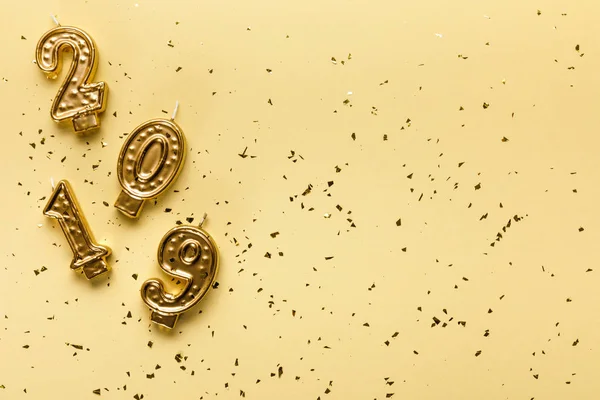 2019 numbers candles and golden confetti on beige background — Stock Photo