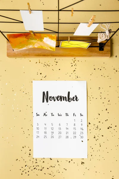 Vue du haut du calendrier de novembre avec confettis dorés et cartes avec pinces à linge sur beige — Photo de stock