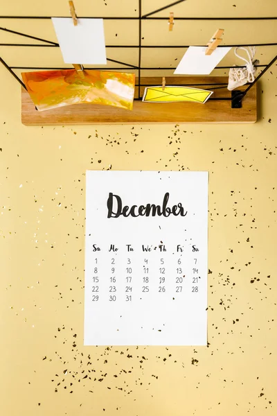 Vista superior do calendário de dezembro com confete dourado e cartões com espinhas de roupa em bege — Fotografia de Stock