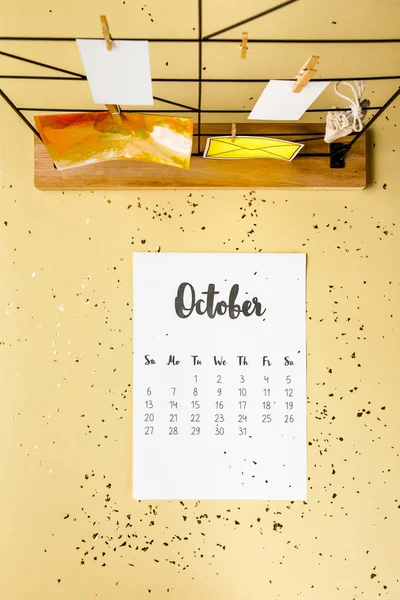 Top view of october calendar with golden confetti and cards with clothespins on beige — Stock Photo