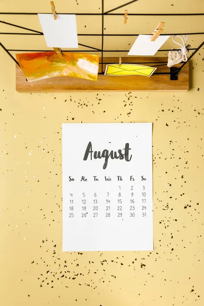 Ansicht des Augustkalenders mit goldenem Konfetti und Karten mit Wäscheklammern auf beige — Stockfoto