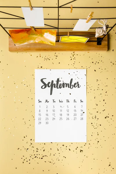 Vista superior do calendário de setembro com confete dourado e cartões com espinhas de roupa em bege — Fotografia de Stock