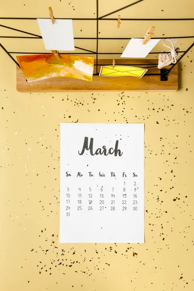 Top view of march calendar with golden confetti and cards with clothespins on beige — Stock Photo