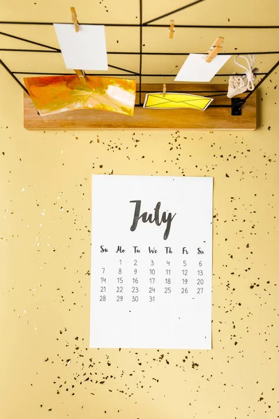 Top view of july calendar with golden confetti and cards with clothespins on beige — Stock Photo