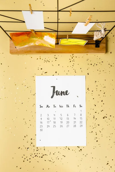 Top view of june calendar with golden confetti and cards with clothespins on beige — Stock Photo