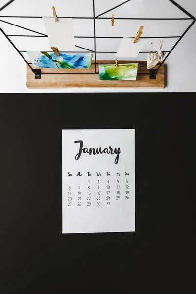 Vue du haut du calendrier de janvier sur noir et cartes avec des peintures abstraites sur blanc — Photo de stock