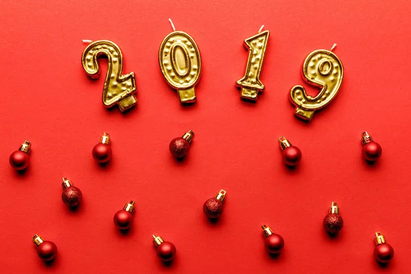 Vue du dessus des bougies dorées 2019 et des boules de Noël rouges sur rouge — Photo de stock