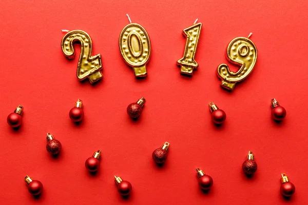 Blick von oben auf goldene Kerzen und rote Christbaumkugeln auf rot — Stockfoto