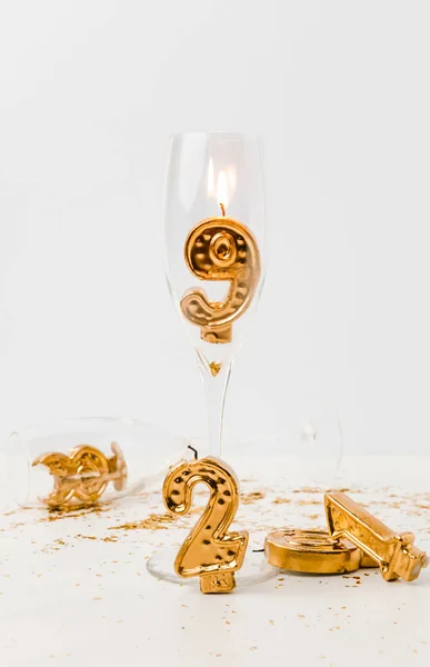 Close-up view of champagne glasses and golden 2019 numbers with burning candle on white — Stock Photo