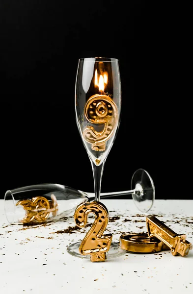 Vista da vicino di bicchieri di champagne e numeri dorati 2019 con candela accesa sul nero — Foto stock