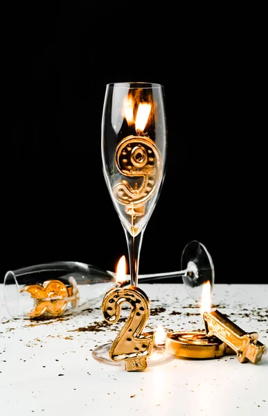 Vue rapprochée des verres à champagne et des numéros dorés 2019 avec des bougies sur noir — Photo de stock