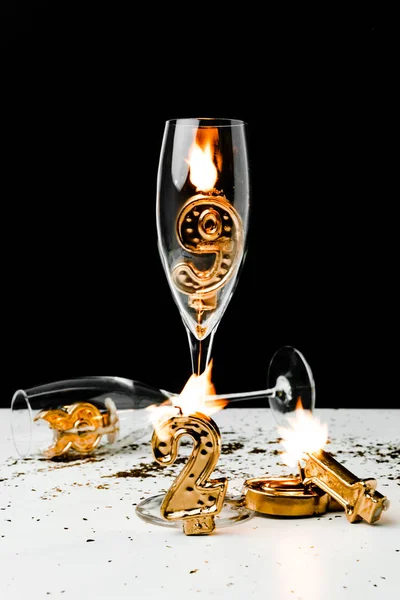 Vista da vicino di bicchieri di vino e numeri dorati 2019 con candele sul nero — Foto stock