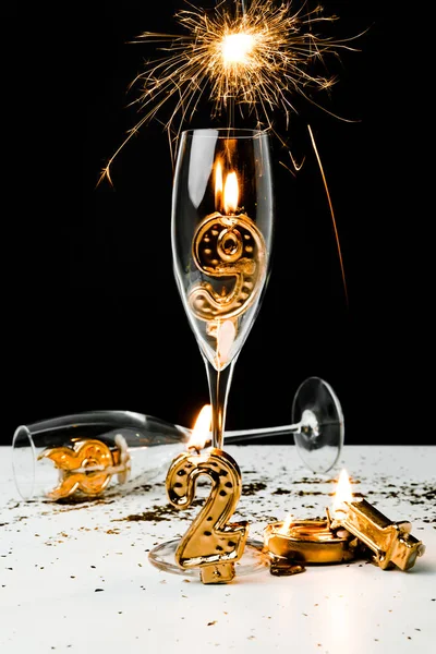 Spumante, bicchieri di vino e numeri dorati 2019 con candele su nero — Foto stock