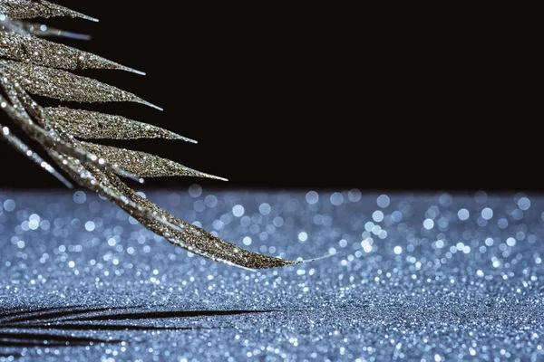 Fuoco selettivo di ramo festivo decorato da scintillio d'oro e ombra su nero — Foto stock