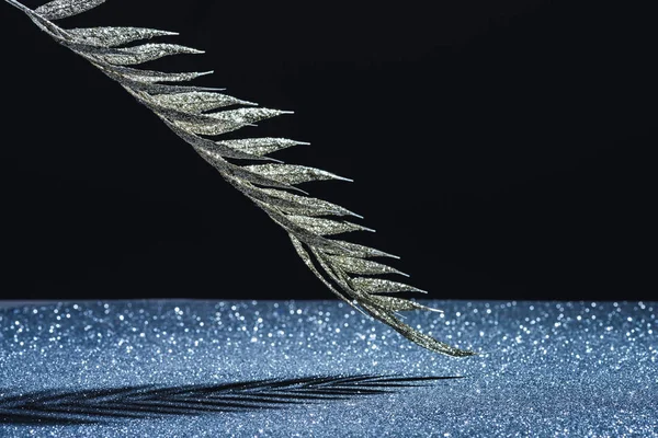 Festive branch decorated by golden glitter and shadow on black — Stock Photo