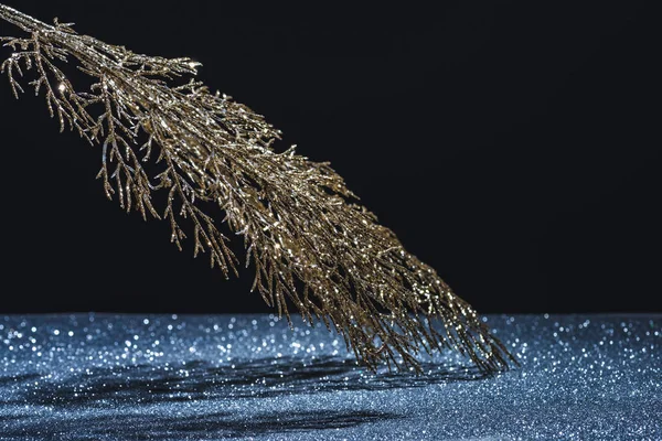 Close up view of festive branch decorated by golden glitter and shadow on black — Stock Photo