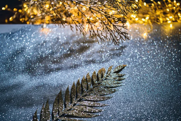 Festliche Zweige mit goldenem Glitzern auf glitzernder Oberfläche — Stockfoto