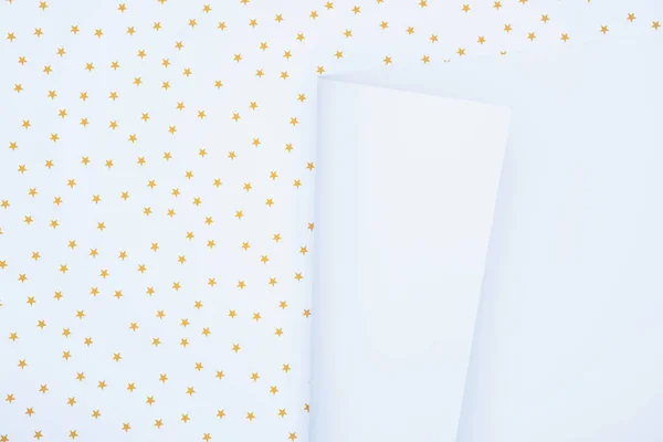 Vista elevada del papel blanco vacío sobre la superficie festiva decorada por estrellas doradas - foto de stock