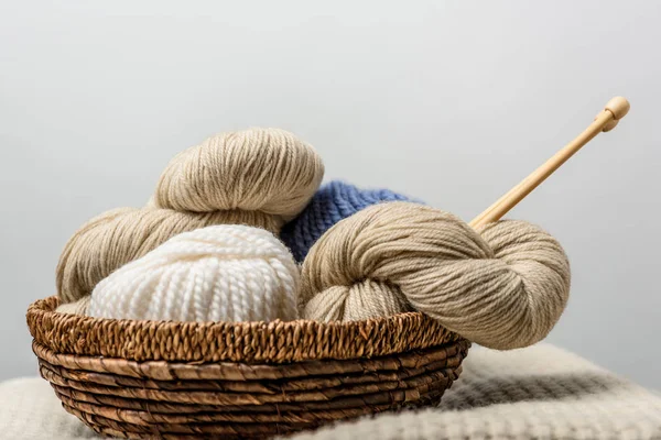 Vue rapprochée du tricot avec des aiguilles à tricoter dans le panier en osier sur fond gris — Photo de stock