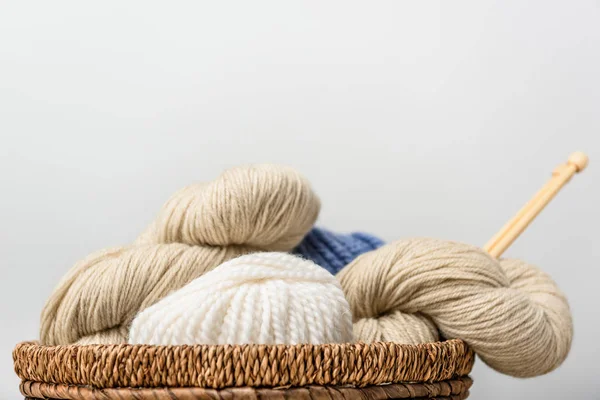 Vista de perto de tricô com agulhas de tricô em cesta de vime em fundo cinza — Fotografia de Stock