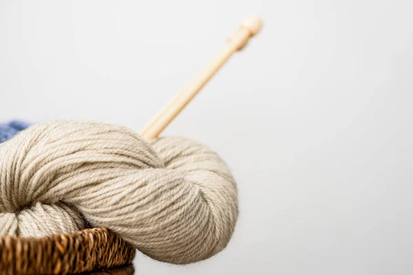 Close up view of beige yarn with knitting needles on grey background — Stock Photo