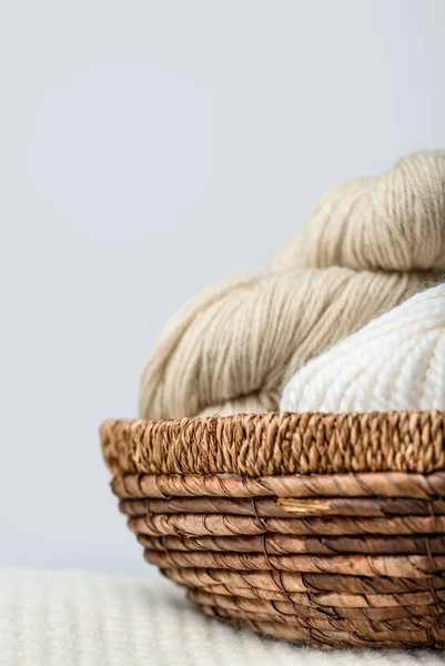 Close up view of yarn cleans in wicker basket on grey backdrop — стоковое фото