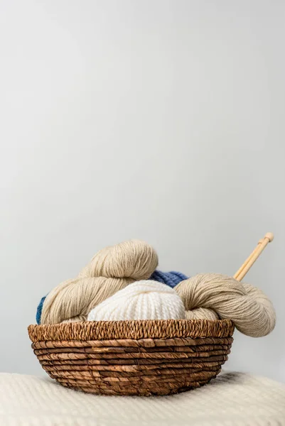 Close up view of yarn clews in wicker basket on grey backdrop — Stock Photo