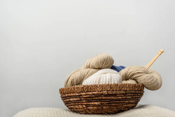 Close up view of yarn cleans in wicker basket on grey backdrop — стоковое фото