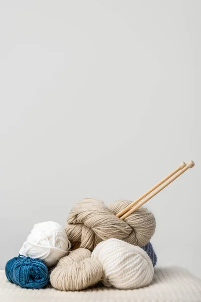 Vista de perto de agulhas de tricô em fendas de fio no fundo cinza — Fotografia de Stock