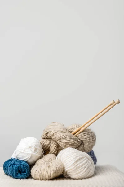 Close up view of knitting needles in yarn clews on grey background — Stock Photo