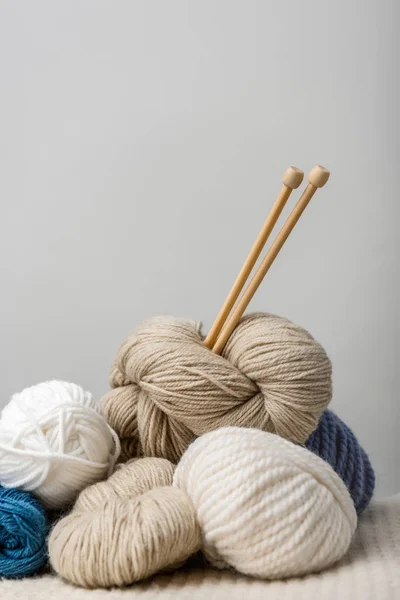 Close up view of knitting needles in yarn clews on grey background — Stock Photo