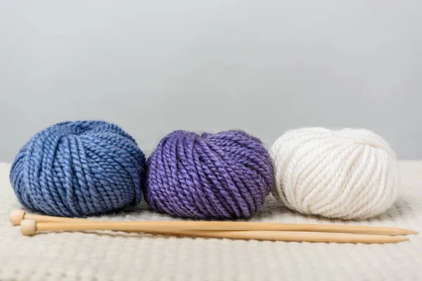 Close up view of arranged yarn balls and knitting needles on grey backdrop — Stock Photo