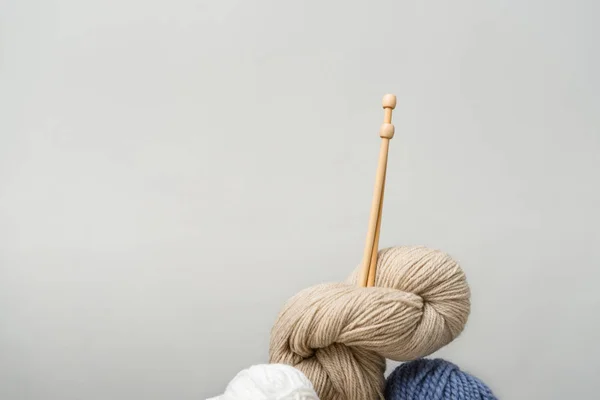 Close up view of knitting clews with knitting needles on grey backdrop — Stock Photo