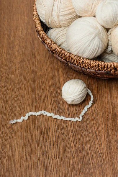 Vue rapprochée des boules de tricot dans un panier en osier sur une table en bois — Photo de stock